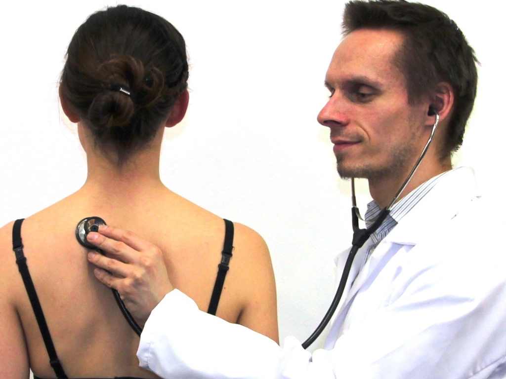 Heilpraktiker untersucht Patientin mit einem Stethoskop